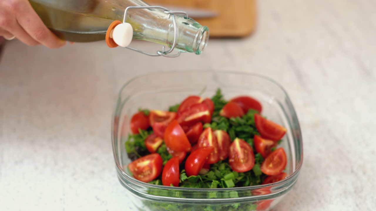Woman pouring oil in a tomato salad