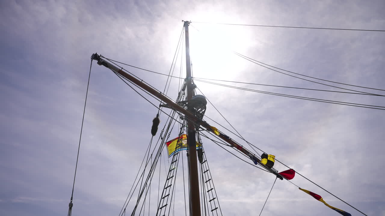 Looking up at the mast of a tall ship with the sun behind