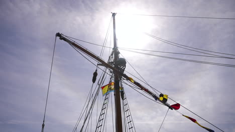 looking up at the mast of a tall ship with the sun behind
