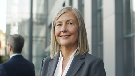 close up view of mature businesswoman in the street and looking and smiling to the camera