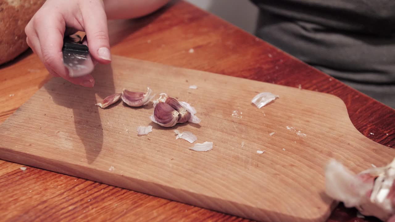 Woman's hands peeling garlic on a chopping board