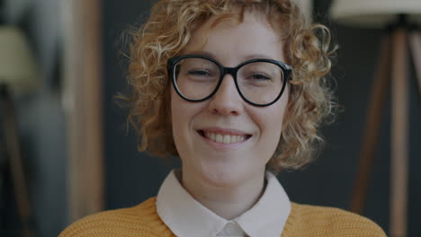 mujer sonriente con cabello rizado y gafas