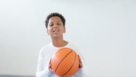 young boy focusing on basketball practice in school gym, holding ball, copy space