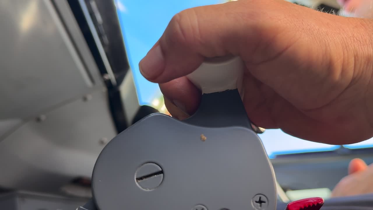 Primer plano, ángulo bajo, de la mano de un piloto caucásico ajustando las palancas de empuje en un vuelo real.