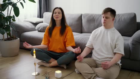 retrato de una mujer ayudando a un hombre con síndrome de down a meditar en casa, cámara lenta