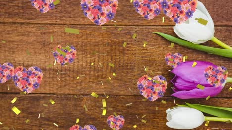 animation of gold confetti falling and flower hearts rising, on black