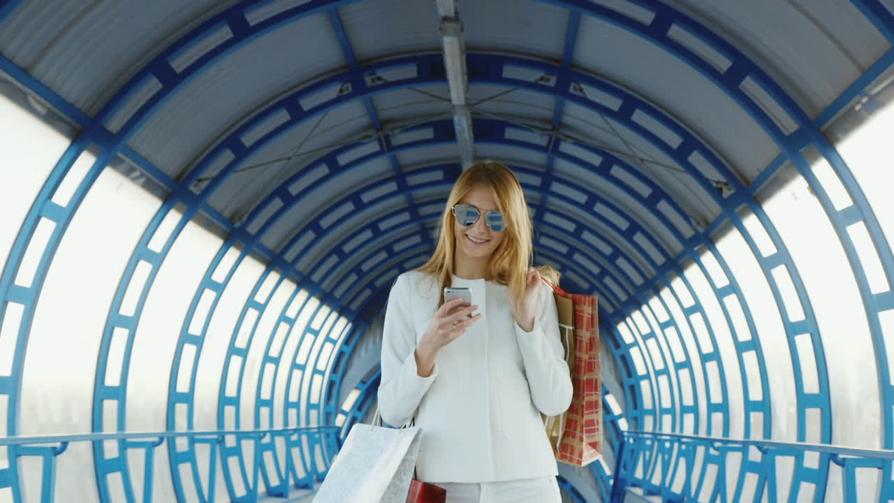 세련된 여성이 쇼핑백을 들고 전화로 성공적인 쇼핑 개념을 이야기합니다.