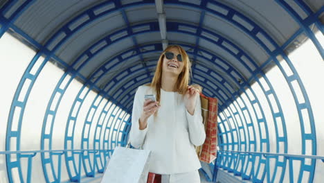 A-Stylish-Woman-Comes-With-Shopping-Bags-Talking-On-The-Phone-Successful-Shopping-Concept