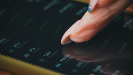 hand of a girl trader touches the display of stock market quotes on a smartphone