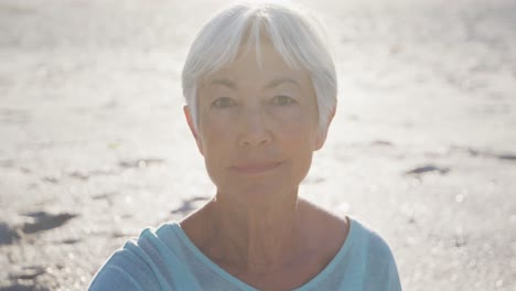 Senior-Caucasian-woman-enjoying-time-at-the-beach-with-sea-in-the-background