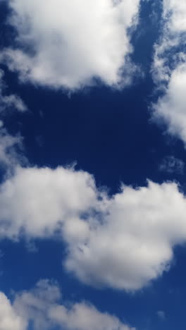white cotton clouds floating fast in the sky. blue summer sky with beautiful clouds. time lapse. vertical video