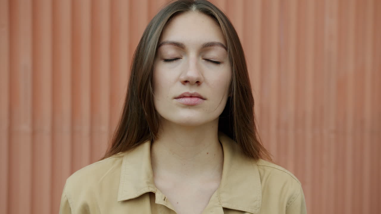 Woman with closed eyes in front of an orange wall