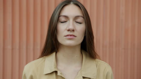 woman with closed eyes in front of an orange wall