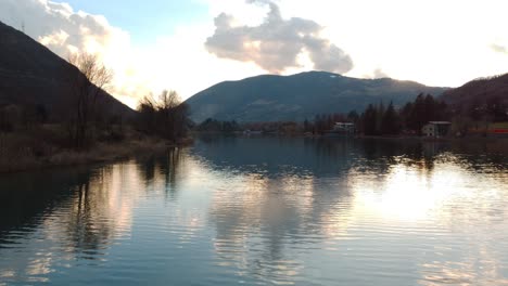 Niedrige-Luftaufnahme-Des-Endine-Sees-In-Italien-Bei-Sonnenuntergang,-Der-über-Stillem-Wasser-Fliegt