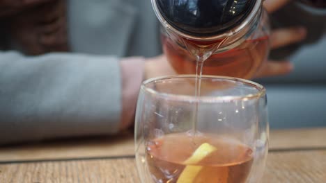 pouring tea into a glass with lemon