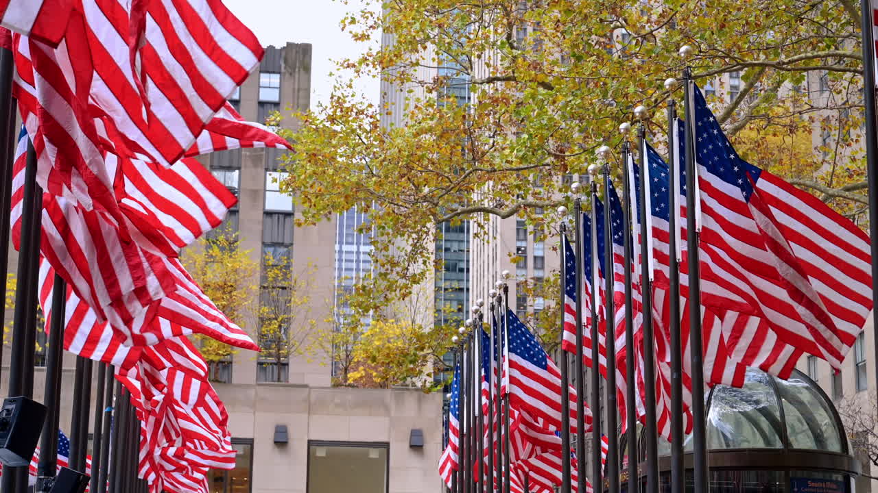 New York, USA, 8 November 2025: Crowds under US flags at Rockefeller. Visitors gather beneath rows of American flags in the busy Rockefeller Center plaza