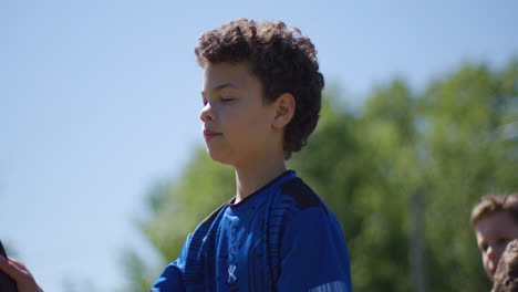 handsome young boy receiving and throwing toy axe outdoors in a park midday