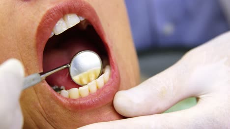 dentist examining a female patient with dental tools