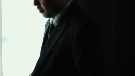 hombre de negocios confiado ajustar traje azul clásico con corbata cerca de la ventana en la habitación del hotel. hombre guapo con un buen traje en el día de la boda.