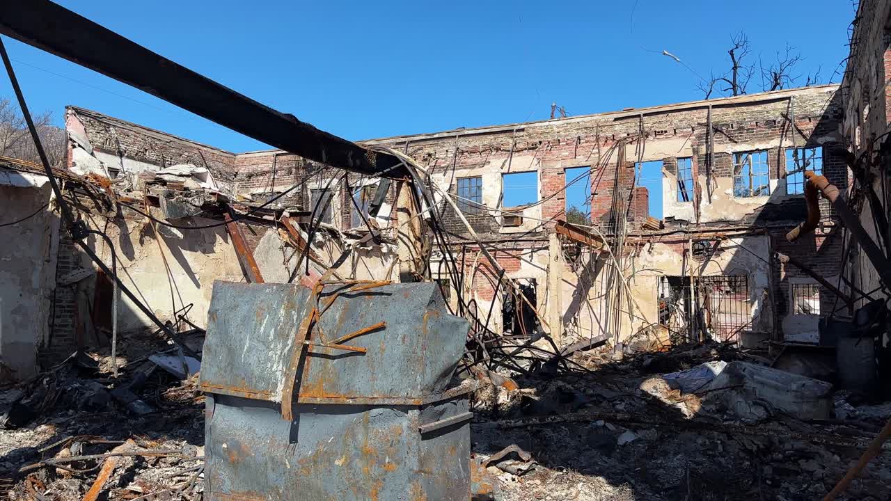 Handheld wide booming down shot of a commercial building burned by the Eaton Fire in Altadena, California. 4K
