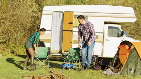 Relaxed couple setting up their camping chairs