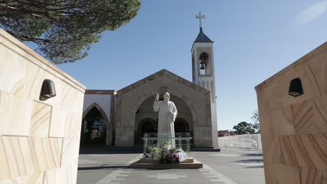 church with bell tower - jesus statue surrounded by flowers