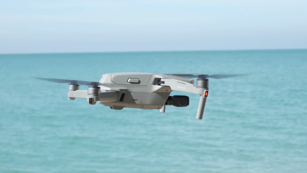 바다와 푸른 하늘을 배경으로 떠다니는 무인 항공기의 측면 보기