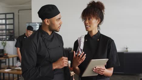 cocineros de raza mixta masculinos y femeninos que usan tableta digital