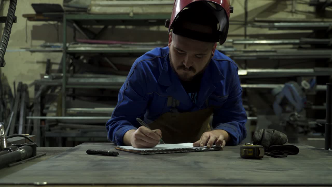 Meccanico concentrato in officina che prende appunti su un blocco note.