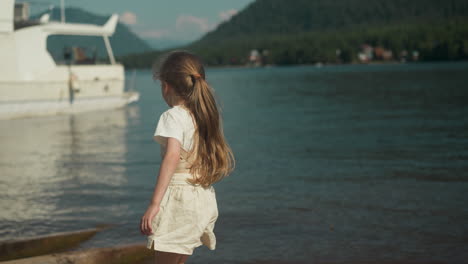 active girl runs to yacht moored by seashore on warm day in summer. entertainment and water transport with scenic sea view in sunny weather