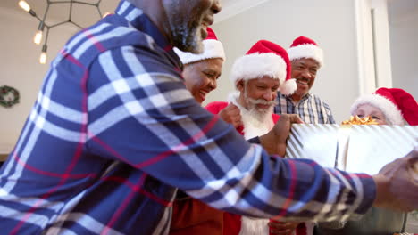 Fröhliche,-Abwechslungsreiche-Seniorenfreunde-Im-Weihnachtsmann-Outfit-Und-Weihnachtsmützen-Tauschen-Zu-Hause-Geschenke-Aus,-Zeitlupe