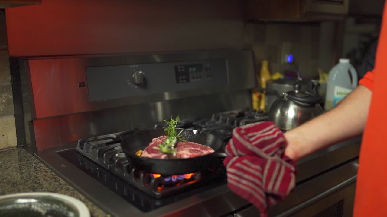 Slo-mo footage moving in on a steak being seasoned and cooked in a cast iron frying pan.