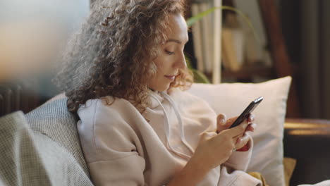 woman using smartphone on couch