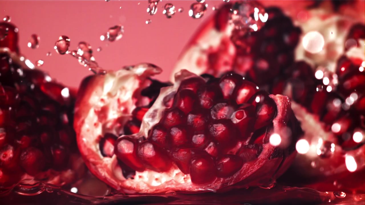 Slowmotion: Vand sprøjter på frisk rødt granatæble