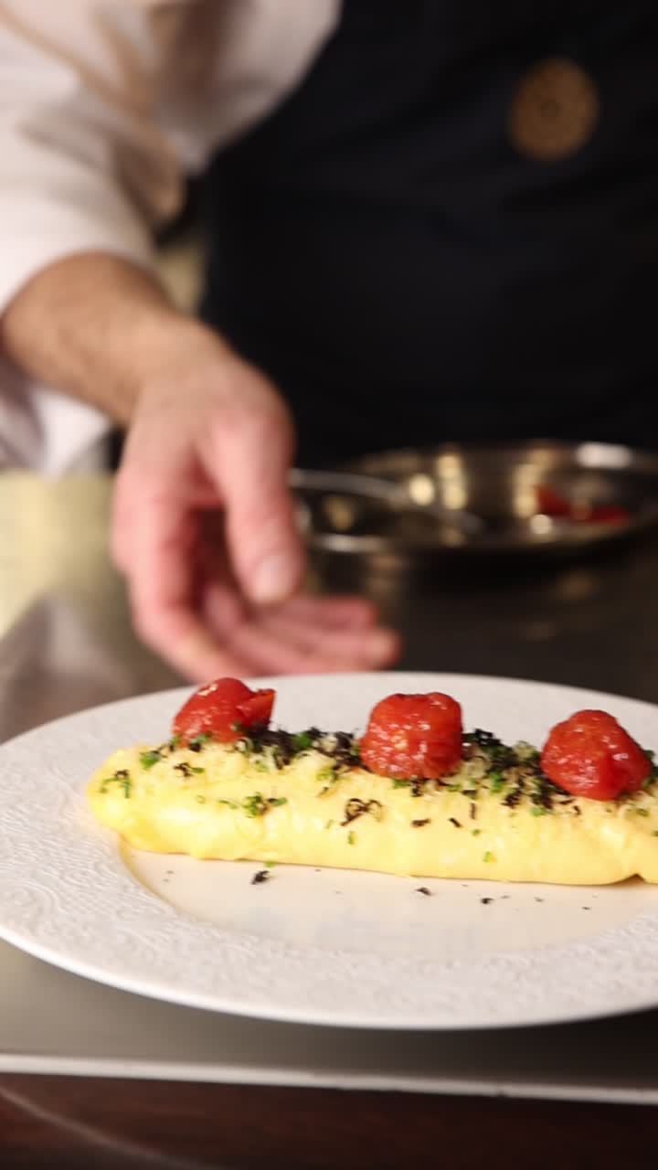 Chef che presenta un piatto gourmet di omelette con pomodori ed erbe aromatiche