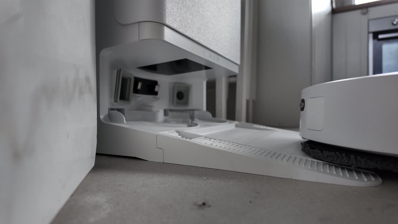 Slow-motion shot of a robot vacuum approaching its automated cleaning base