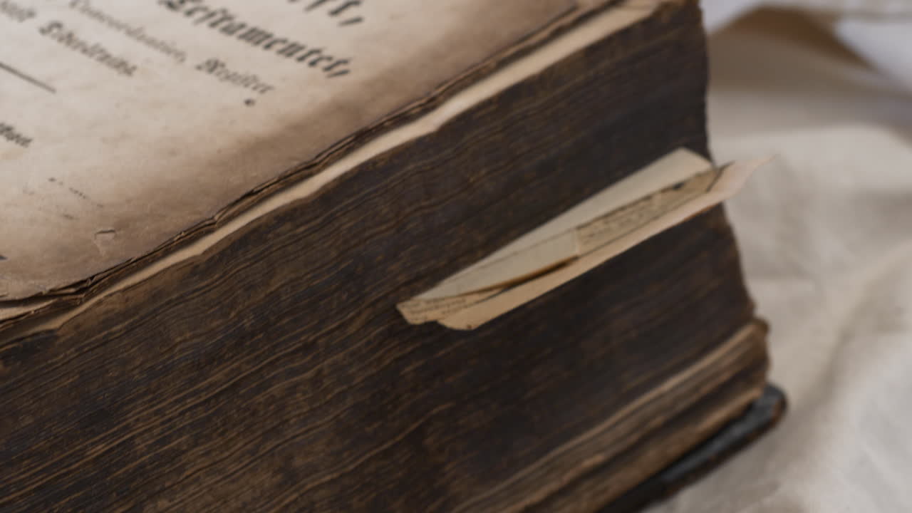 흰색 시트에 스웨덴어로 된 고대 무거운 낡은 성경을 따라 팬을 닫습니다.