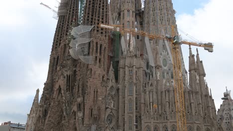 Tilting-shot-showcasing-the-Sagrada-Familia,-the-largest-unfinished-Catholic-church-in-the-world-and-part-of-a-UNESCO-World-Heritage-Site