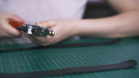 designer rotates hole punch pliers and takes leather cloth