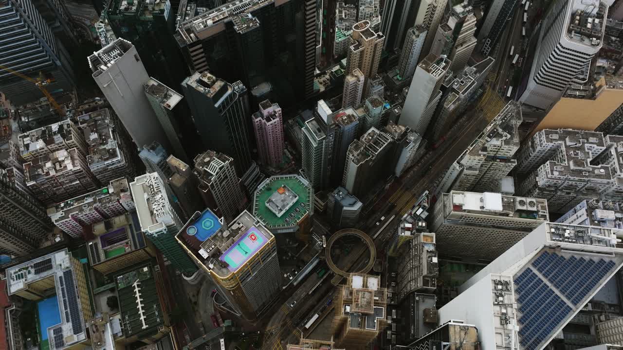 Vista aérea con inclinación sobre calles y rascacielos en el centro de Hong Kong, día nublado.