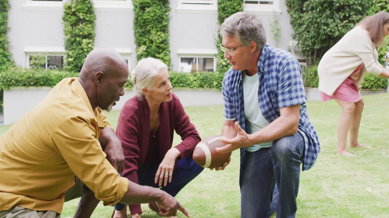 Animation of happy diverse female and male senior friends playing american football in garden