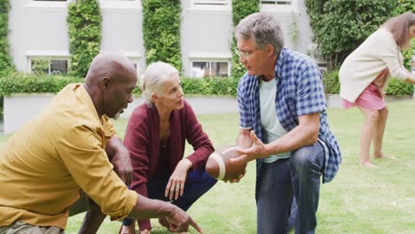 Animation-of-happy-diverse-female-and-male-senior-friends-playing-american-football-in-garden