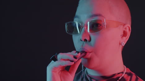 stylish woman vaping in neon lighting