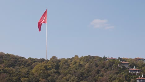 Bright-red-National-flag-of-Turkey-flies-slowly-on-urban-hillside