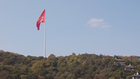 bright red national flag of turkey flies slowly on urban hillside