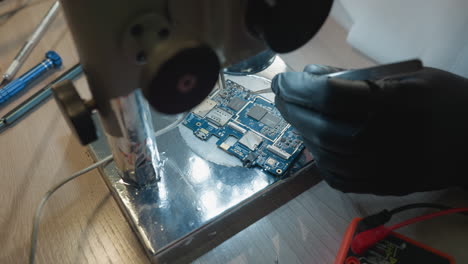 close-up view of a technician working on a circuit board on a lab workbench, various precision tools, including tweezers and screwdrivers, are scattered around