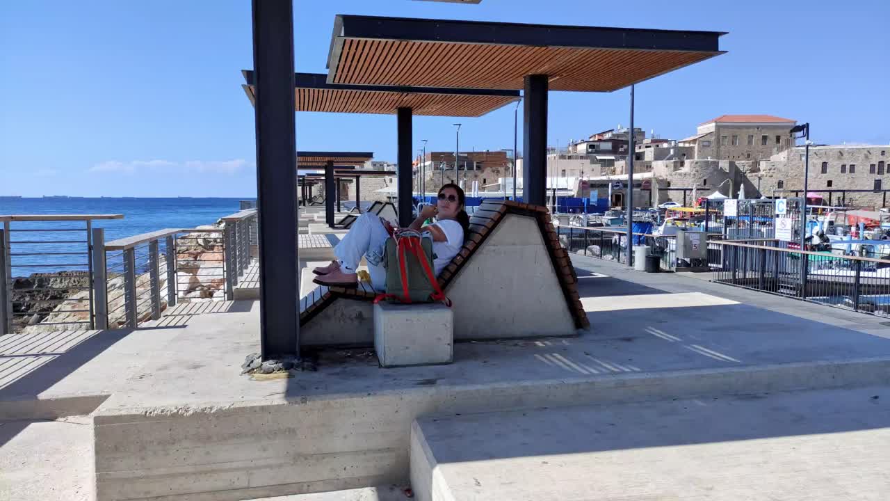 Tourist relaxing on a bench looking at the Mediterranean Sea view