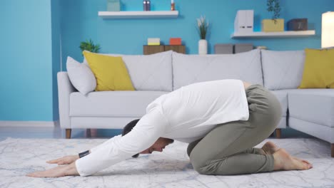 joven haciendo calentamiento y ejercicios de estiramiento en casa, haciendo balasana.