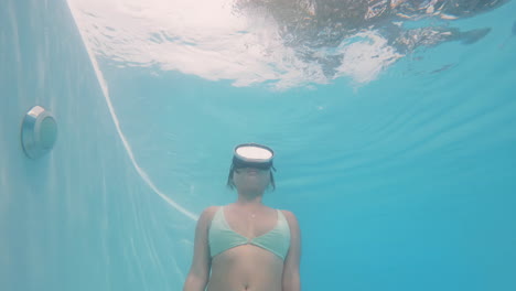 Pretty-Girl-in-Swimsuit-Underwater-with-Vintage-Diving-Goggles-Surfacing