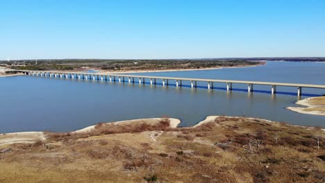 flying diagonally over the shoreline towards the large 4 lane bridge crossing the lake